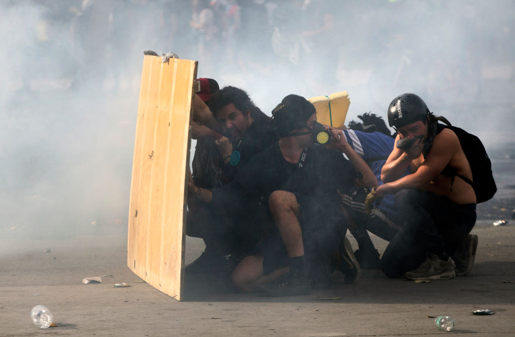 OPSHOT - Demonstrators clash with riot police on the fifth straight day of street violence which erupted over a now suspended hike in metro ticket prices, in Santiago, on October 22, 2019. - President Sebastian Pinera held a meeting with leaders of some of Chile's opposition parties on Tuesday, aiming to find a way to end street violence that has claimed 15 lives amid sustained protests. (Photo by CLAUDIO REYES / AFP) (Photo by CLAUDIO REYES/AFP via Getty Images)