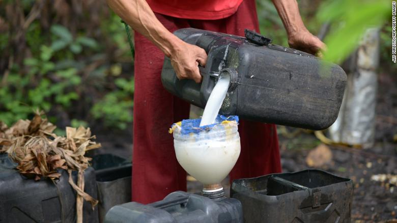 TO GO WITH AFP STORY "Philippines-lifestyle-drink-wine,FEATURE" by Jason Gutierrez In this photo taken on November 15, 2012, tapper Eugenio Andaya, pours his harvest of coconut sap to be used in a local wine called 'tuba' the raw material for Lambanog in Tayabas, Quezon Province, south of Manila. With their huge copper vats and open fires, little-known backyard liquor makers have toiled for generations in Philippine coconut farms to distill the country's answer to Russian vodka. Extracted from the sap of the coconut, the "lambanog" was once considered a lowly peasant's drink whose potency they claim puts those of well-known liquors and spirits around the world in the shade. AFP PHOTO / JAY DIRECTO (Photo credit should read JAY DIRECTO/AFP via Getty Images)