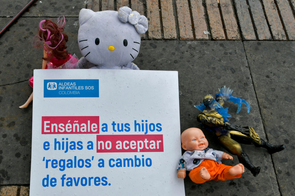 Toys are displayed next to a sign reading "Teach your children not to accept presents in exchange of favours" at the Bolivar square in Bogota, on November 20, 2019, as part of a campaign to raise awareness against child abuse during the universal Children's Day. - World Children's Day was first established in 1954 and is celebrated on November 20th to promote international awareness among children worldwide and improving their welfare. (Photo by Raul ARBOLEDA / AFP) (Photo by RAUL ARBOLEDA/AFP via Getty Images)