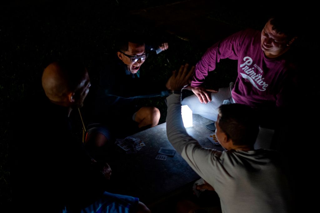 A group of young men play cards in the outdoors lit by a solar rechargeable lamp after an earthquake hit the island in Guanica, Puerto Rico on January 8, 2020. - Puerto Rico's governor declared a state of emergency on Tuesday after a powerful 6.4 magnitude earthquake killed at least one person in the south of the island and caused widespread damage. Governor Wanda Vazquez said the declaration would allow for the activation of National Guard troops in the US territory still recovering from a devastating 2017 hurricane. (Photo by Ricardo ARDUENGO / AFP) (Photo by RICARDO ARDUENGO/AFP via Getty Images)
