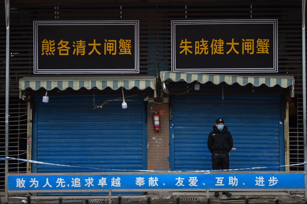 TOPSHOT - A security guard stands outside the Huanan Seafood Wholesale Market where the coronavirus was detected in Wuhan on January 24, 2020 - The death toll in China's viral outbreak has risen to 25, with the number of confirmed cases also leaping to 830, the national health commission said. (Photo by Hector RETAMAL / AFP) (Photo by HECTOR RETAMAL/AFP via Getty Images)