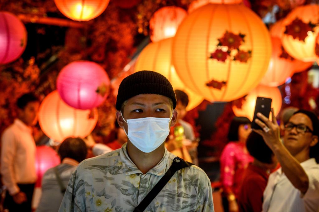 A man with a face mask walks in a shop decorated for the Chinese Lunar New Year in Bangkok on January 24, 2020, after four people were detected with the Coronavirus in Thailand. (Photo by Mladen ANTONOV / AFP) (Photo by MLADEN ANTONOV/AFP via Getty Images)