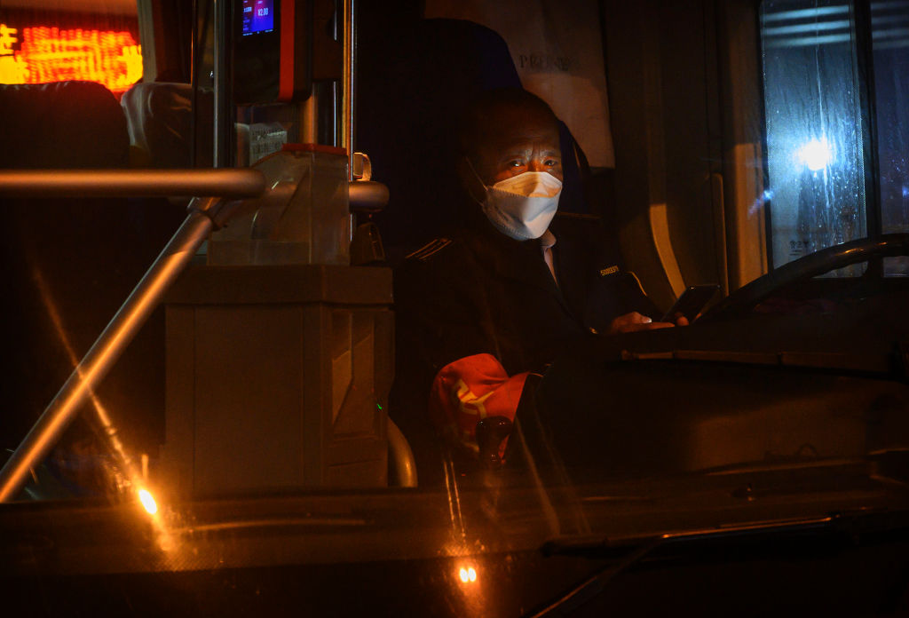 BEIJING, CHINA - FEBRUARY 13: A Chinese bus driver wears a protective mask as he waits in his bus on February 13, 2020 in Beijing, China. The number of cases of the deadly new coronavirus COVID-19 rose to more than 52000 in mainland China Thursday, in what the World Health Organization (WHO) has declared a global public health emergency. China continued to lock down the city of Wuhan in an effort to contain the spread of the pneumonia-like disease which medicals experts have confirmed can be passed from human to human. In an unprecedented move, Chinese authorities have maintained and in some cases tightened the travel restrictions on the city which is the epicentre of the virus and also in municipalities in other parts of the country affecting tens of millions of people. The number of those who have died from the virus in China climbed to over 1300 on Thursday, mostly in Hubei province, and cases have been reported in other countries including the United States, Canada, Australia, Japan, South Korea, India, the United Kingdom, Germany, France and several others. The World Health Organization has warned all governments to be on alert and screening has been stepped up at airports around the world. Some countries, including the United States, have put restrictions on Chinese travellers entering and advised their citizens against travel to China. (Photo by Kevin Frayer/Getty Images)