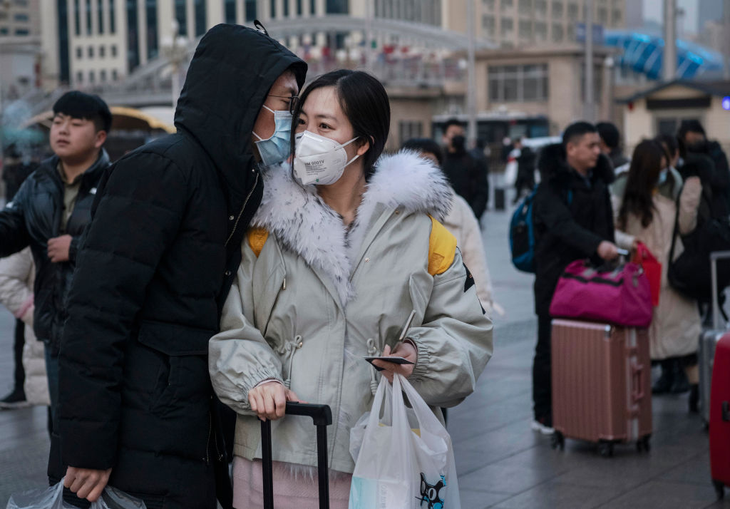 BEIJING, CHINA - JANUARY 21: A Chinese man kisses his partner goodbye while both wear protective masks as she leaves to travel home at Beijing Railway station before the annual Spring Festival on January 21, 2020 in Beijing, China. The number of cases of a deadly new coronavirus rose to nearly 300 in mainland China Tuesday as health officials stepped up efforts to contain the spread of the pneumonia-like disease which medicals experts confirmed can be passed from human to human. The number of those who have died from the virus in China climbed to six on Tuesday and cases have been reported in other parts of Asia including in Thailand, Japan, Taiwan and South Korea. (Photo by Kevin Frayer/Getty Images)