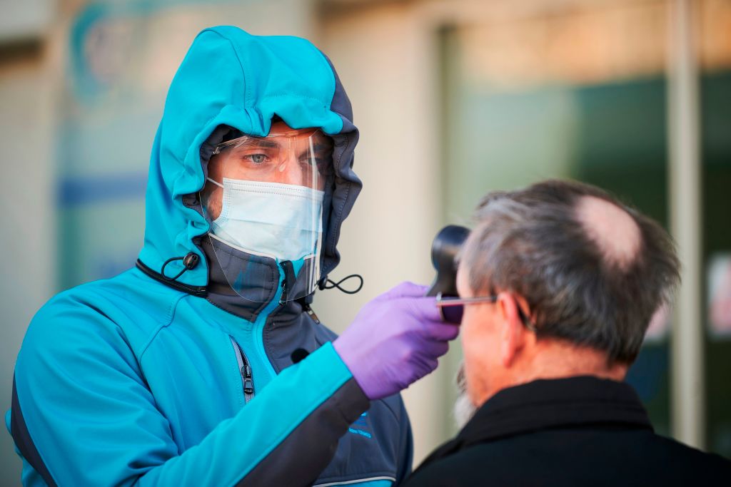 TOPSHOT - A medical worker measures body temperature at one of the entrances of the Community Health Centre in Kranj, Slovenia on March 23, 2020 amid concerns over the spread of the COVID-19 coronavirus. (Photo by Jure Makovec / AFP) (Photo by JURE MAKOVEC/AFP via Getty Images)