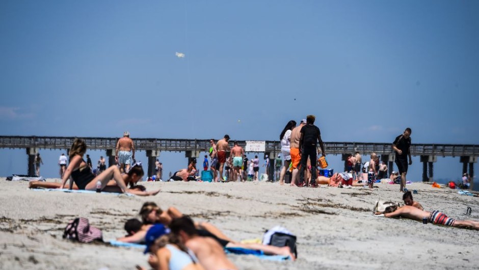 People relax on the Beach amid the Coronavirus pandemic in Tybee Island, Georgia on April 25, 2020. - After being locked down for weeks, many residents in Georgia are thumbing their noses at the deadly coronavirus and seeking sanctuary in the sun, sand and waves of the southern state's beaches. Under a cloudless blue sky with balmy temperatures and soft breezes rolling off the water, Tybee Island proved a powerful weekend lure Saturday for Georgians desperate for any return to normalcy -- and an escape from self-imposed isolation. (Photo by CHANDAN KHANNA / AFP) (Photo by CHANDAN KHANNA/AFP via Getty Images)