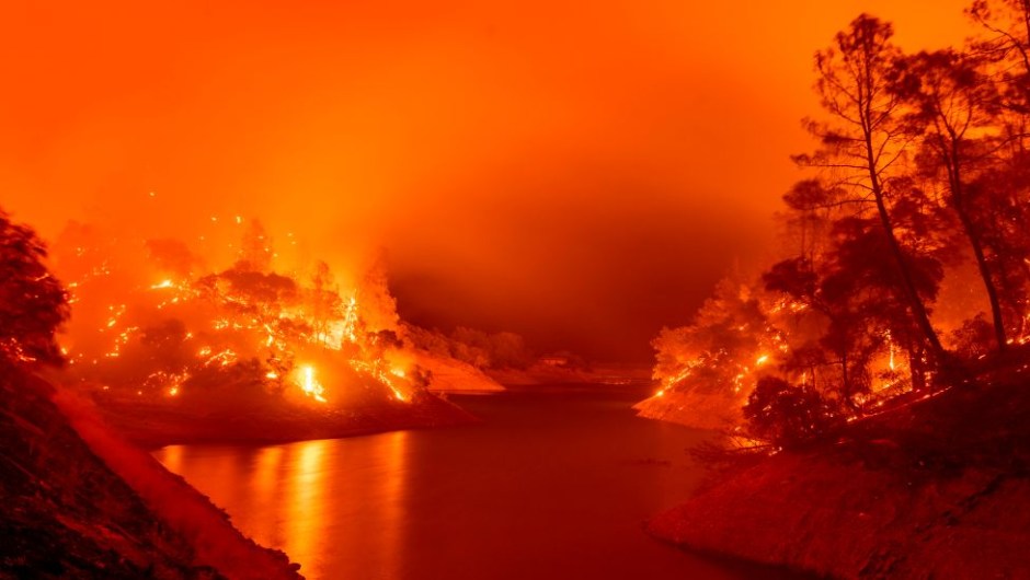 Incendios forestales california afectados hectáreas kilómetros cuadrados fotos videos TOPSHOT - In this long exposure photograph, flames consumes both sides of a segment of Lake Berryessa during the Hennessey fire in the Spanish Flat area of Napa, California on August 18, 2020. - As of the late hours of August 18, the Hennessey fire has merged with at least 7 fires and is now called the LNU Lightning Complex fires. Dozens of fires are burning out of control throughout Northern California as fire resources are spread thin. (Photo by JOSH EDELSON / AFP) (Photo by JOSH EDELSON/AFP via Getty Images)
