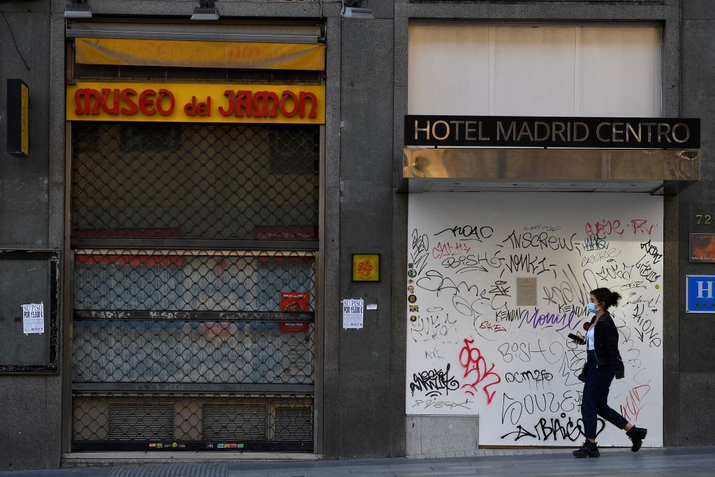 A woman walks past a closed hotel and restaurant on Gran Via, the main avenue of central Madrid, on October 16, 2020. - The coronavirus pandemic has pulverised Spain's tourism-dependent economy, with the government warning that GDP would fall by 11.2 percent this year, down from a previous prediction in May for a 9.2 percent decline. (Photo by GABRIEL BOUYS / AFP) (Photo by GABRIEL BOUYS/AFP via Getty Images)