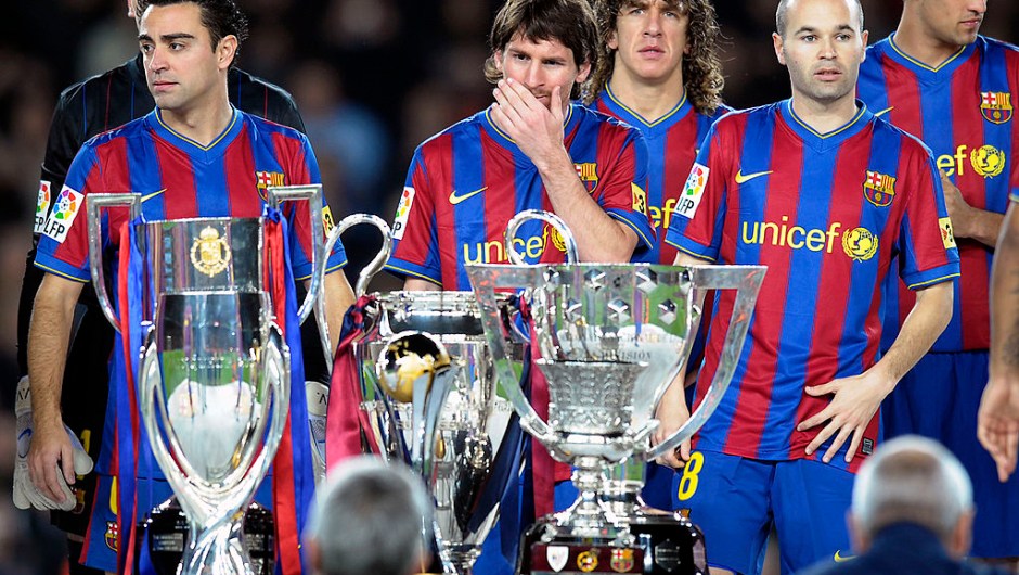(De izquierda a derecha) Xavi, Lionel Messi, Carles Puyol y Andrés Iniesta muestran los seis trofeos de la temporada 2009 antes de su partido de fútbol de liga española contra el Villarreal el 2 de enero de 2010 en el estadio Camp Nou, en Barcelona. (Foto: LLUIS GENE/AFP vía Getty Images)