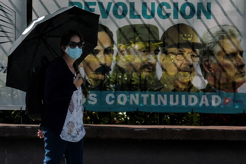 A woman wearing a face mask walks near a poster with images of Cuban revolutionary (L-R) Cuban national hero Jose Marti, Cuban late leader Fidel Castro, the Former First Secretary of the Communist Party Raul Castro and Cuban President Miguel Diaz-Canel, in Havana, on June 3 2021. - Out of the official scene for a month and a half, Cuban leader Raul Castro turns 90 on Thursday, after leaving the leadership of the ruling Communist Party on April 19, his last post. However, his image continues to be a daily sight in the streets of Havana and the official government recalled the date through all its channels. (Photo by YAMIL LAGE / AFP) (Photo by YAMIL LAGE/AFP via Getty Images)