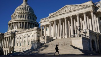 A woman walks past the U.S. Senate and Capitol dome on Capitol Hill in Washington, Thursday, Sept. 30, 2021. Congress is moving to avert one crisis while putting off another with the Senate poised to approve legislation that would fund the federal government into early December. (AP Photo/Patrick Semansky)