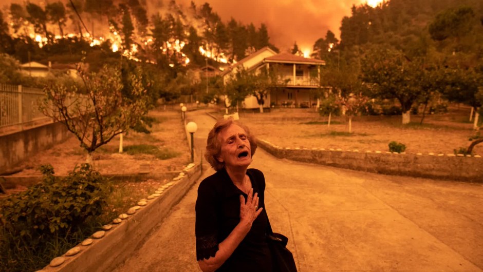 8 de agosto: una mujer reacciona mientras un incendio forestal se acerca a su casa en el pueblo de Gouves, en la isla de Evia, Grecia. Miles de residentes se vieron obligados a huir de Evia, que está a unos 160 kilómetros al norte de Atenas. (Crédito: Konstantinos Tsakalidis/Bloomberg/Getty Images)