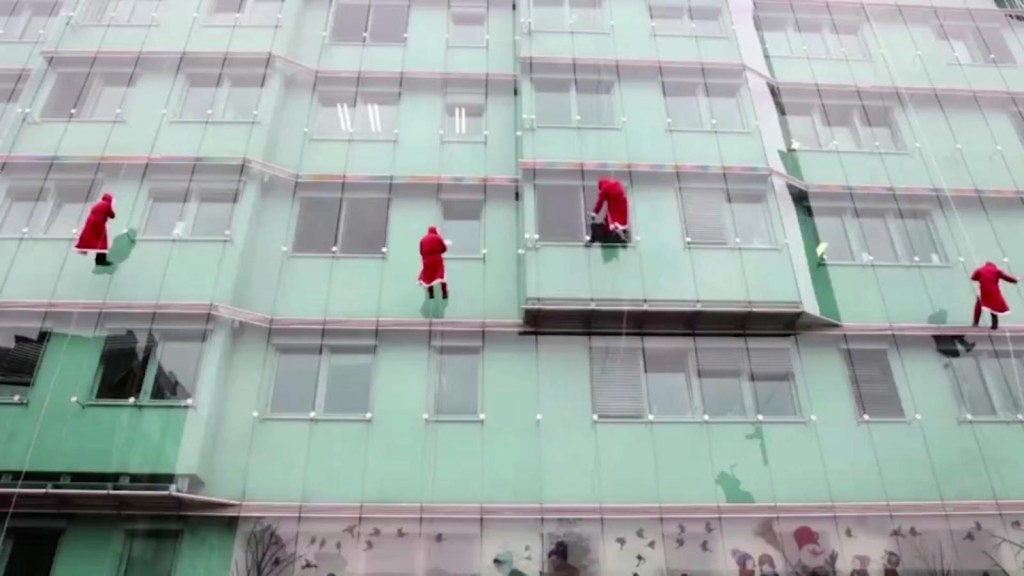 Ejército de Papás Noel desciende por muros de hospitales