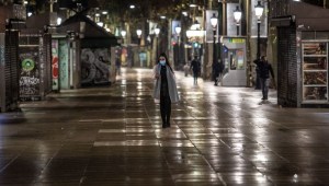 A pedestrian walks in the empty central street of La Rambla, in Barcelona, on the night of December 23 to December 24, 2021, as Spain's Catalonia reimposes a night-time curfew, closes nightclubs and limits social gatherings to fight a record surge in Covid-19 infections. (Photo by ANGEL GARCIA / AFP) (Photo by ANGEL GARCIA/AFP via Getty Images)