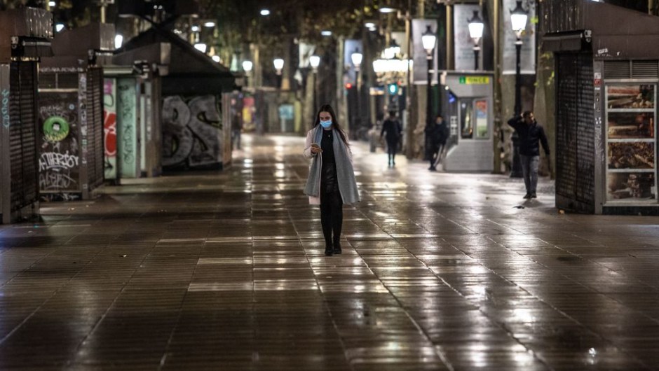 A pedestrian walks in the empty central street of La Rambla, in Barcelona, on the night of December 23 to December 24, 2021, as Spain's Catalonia reimposes a night-time curfew, closes nightclubs and limits social gatherings to fight a record surge in Covid-19 infections. (Photo by ANGEL GARCIA / AFP) (Photo by ANGEL GARCIA/AFP via Getty Images)
