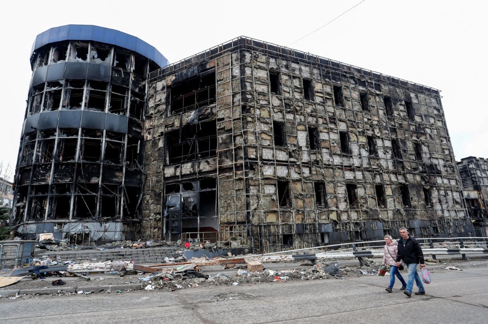 Unas personas pasan por delante de un edificio destruido en Mariupol el 14 de abril. (Alexander Ermochenko/Reuters)