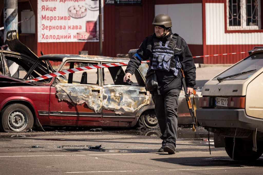 A Ukrainian policeman passes damaged vehicles outside a train station in Kramatorsk, Ukraine, on April 8.  (Fadel Senna / AFP / Getty Images)