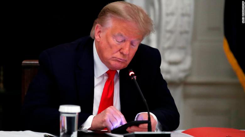 El expresidente Donald Trump mira su teléfono durante una mesa redonda con gobernadores sobre la reapertura de las pequeñas empresas estadounidenses, en el Comedor de Estado de la Casa Blanca en Washington, el 18 de junio de 2020.