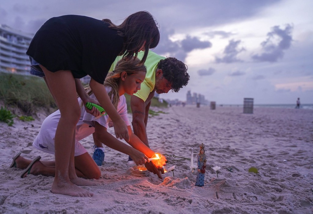 Personas en duelo encienden velas en la playa cerca del edificio. (Foto: Angel Valentin/The New York Times/Redux)