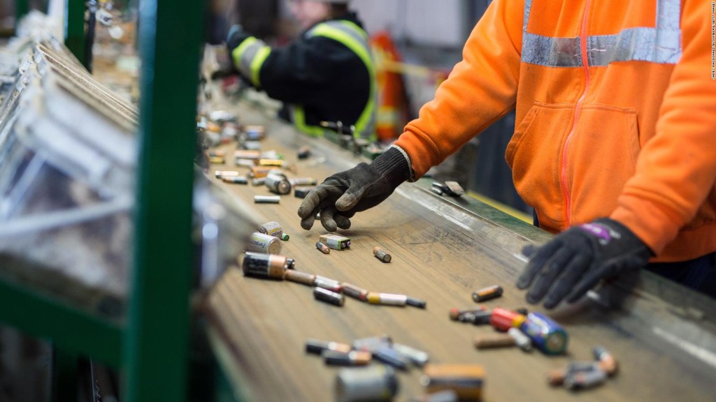 Trabajadores clasifican las baterías que se mueven por una cinta transportadora en una instalación de reciclaje.