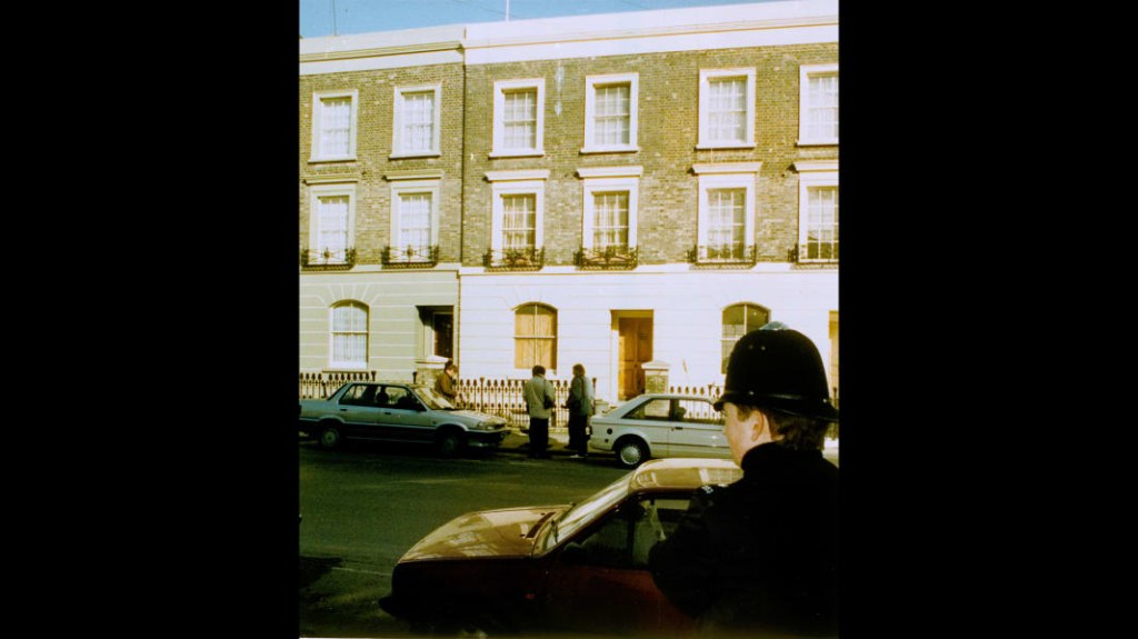 Reporteros parados frente a la casa de Rushdie en Londres el 16 de febrero de 1989, mientras un agente de policía observaba desde el otro lado de la calle. (Crédito: Peter Kemp/AP)