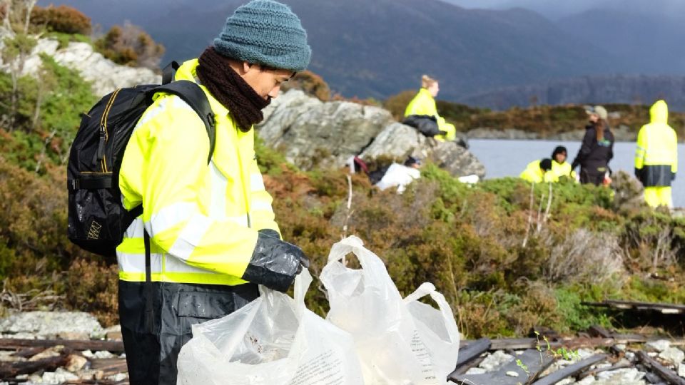 persona recogiendo basura en la costa glacial de Noruega 