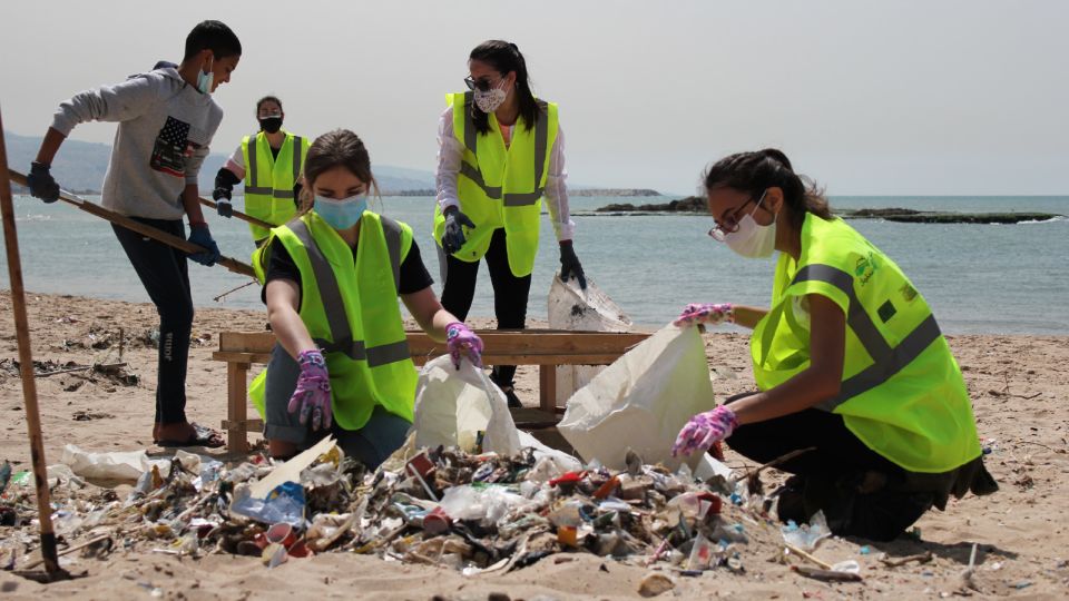 Jóvenes con chalecos amarillos recogiendo basura en una playa de Líbano