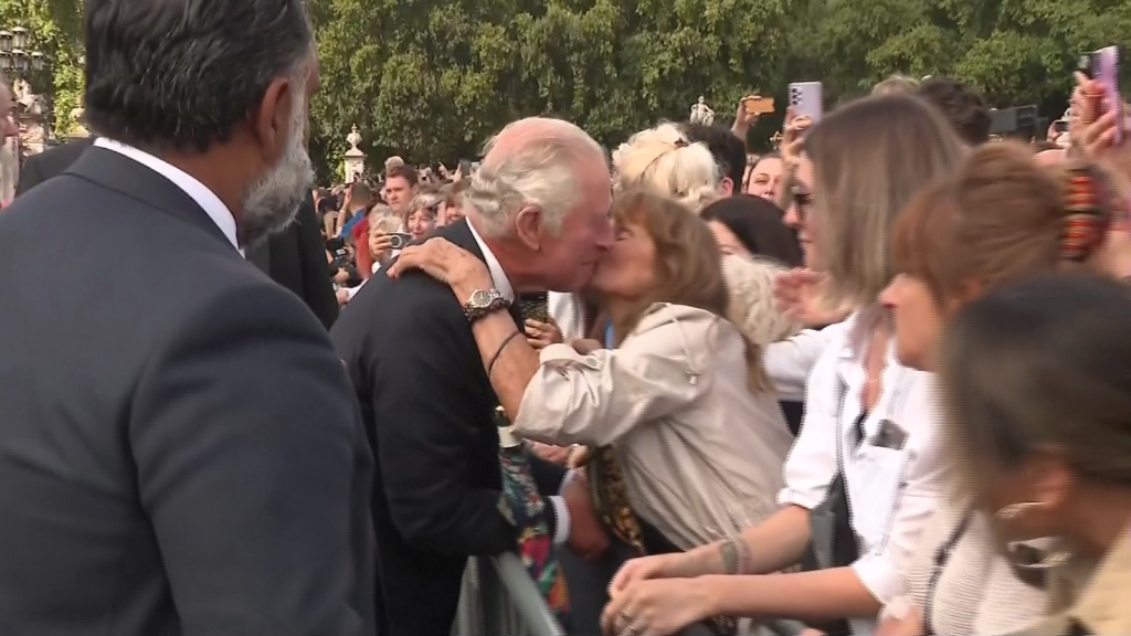 A woman kisses King Charles III outside Buckingham Palace