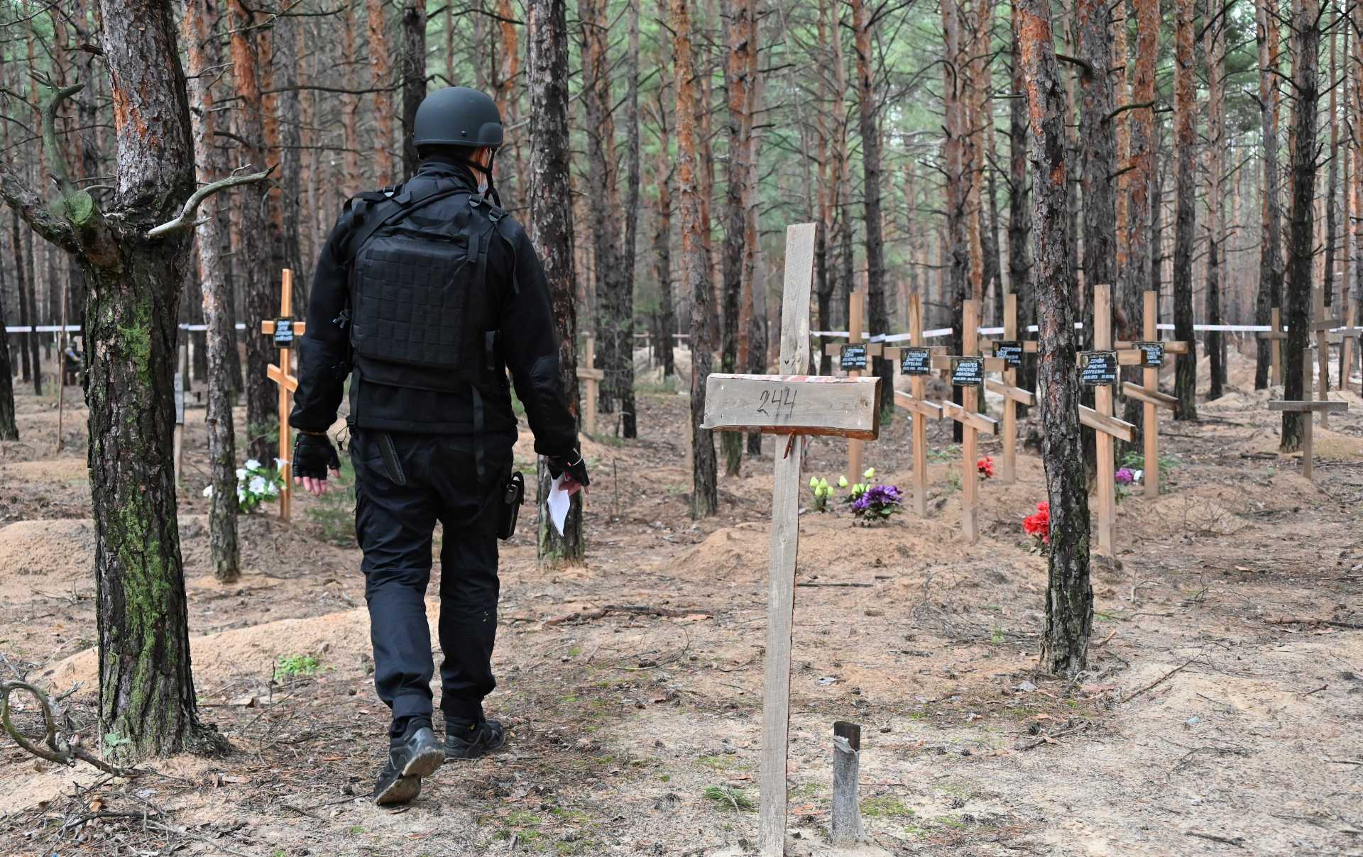 Un oficial de policía ucraniano camina por la fosa común hallada en un bosque en las afueras de Izyum, Ucrania, el 16 de septiembre de 2022.