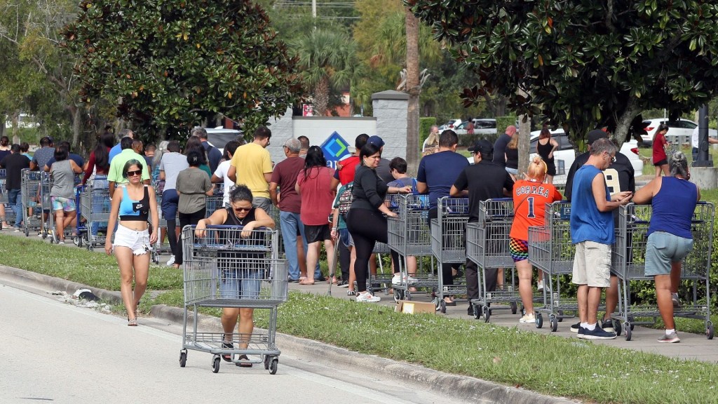 Compradores caminan para unirse a una fila que se extiende más allá del estacionamiento fuera de un almacén de venta al por menor, mientras la gente se apresura a prepararse para la tormenta Ian, en Kissimmee, Florida, el 25 de septiembre de 2022.