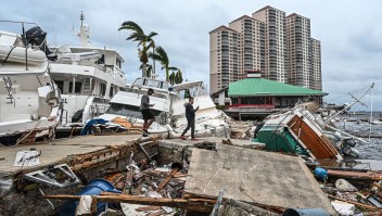 Residentes examinan los daños en un muelle mientras los botes están parcialmente sumergidos tras el paso del huracán Ian en Fort Myers, Florida, el 29 de septiembre de 2022.