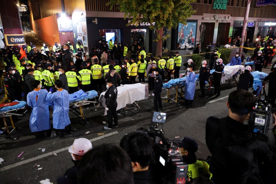 Los miembros del equipo de rescate esperan con camillas para sacar los cuerpos de la escena el sábado por la noche en Itaewon. (Crédito: im hong ji)