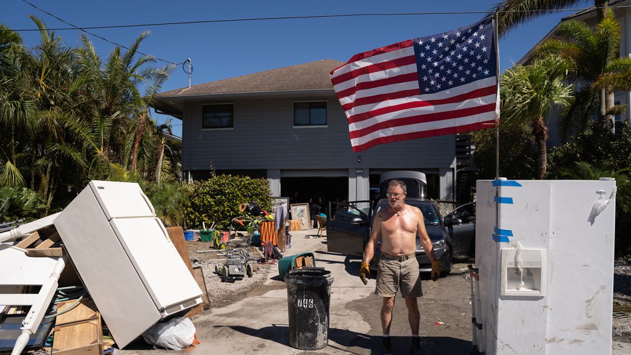 A man stands in front of a house damaged by storm surge in the wake of Hurricane Ian in Naples, Florida.