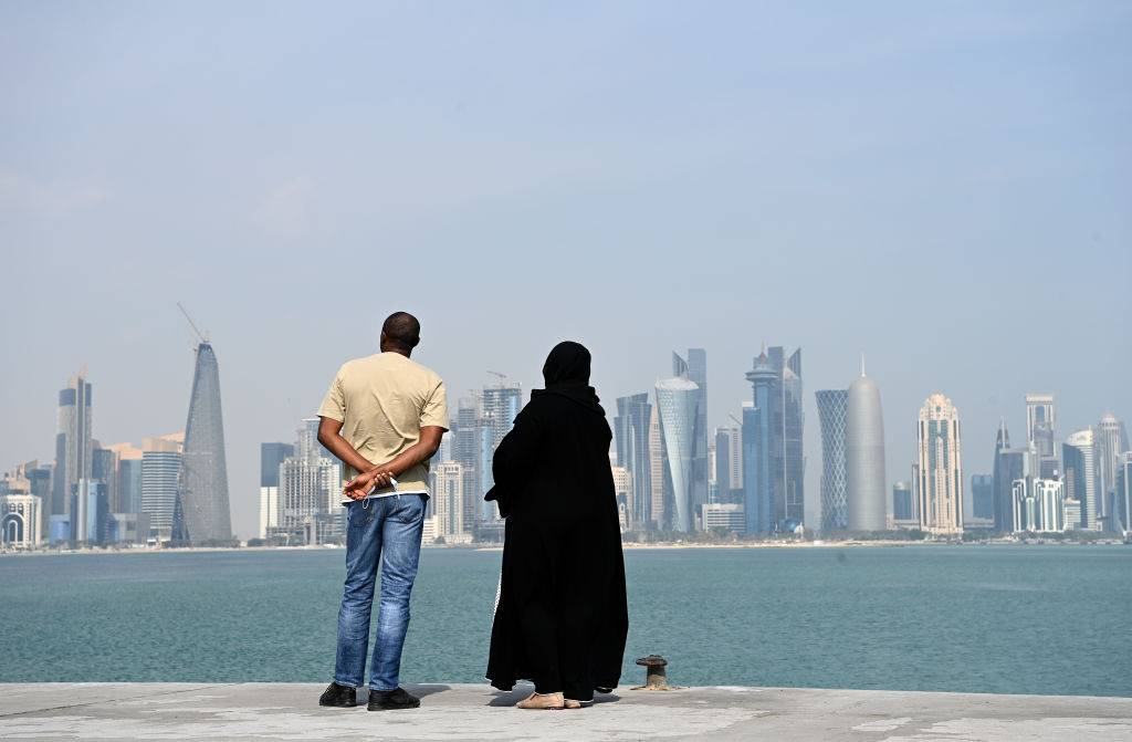 Two people look at the skyscrapers on the coast of Doha, Qatar.