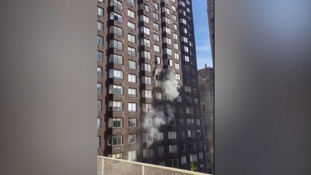 A woman is left hanging from the window of a burning building