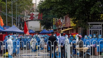 Agentes de la ley con trajes blancos para protección de riesgos se preparan para trasladar a los residentes con ropa de protección azul en un barrio de alto riesgo de Guangzhou el 5 de noviembre. (Foto: Chinatopix/AP)