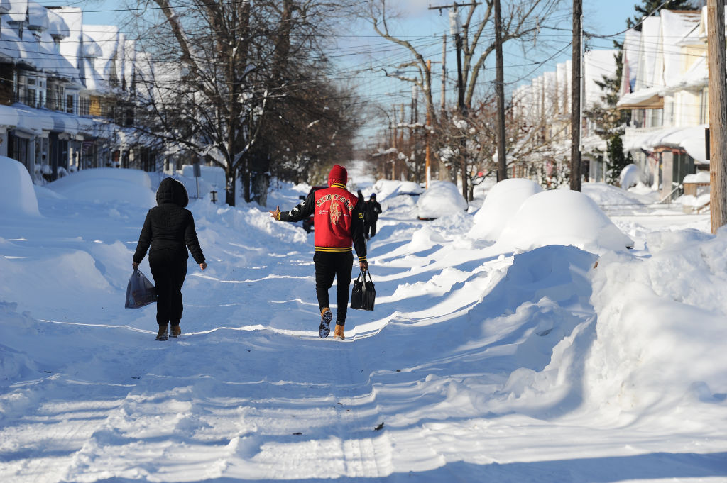 Los peatones recorren calles cubiertas de nieve después de una intensa tormenta de nieve con efecto lago que afectó el área el 20 de noviembre de 2022 en Buffalo, Nueva York.