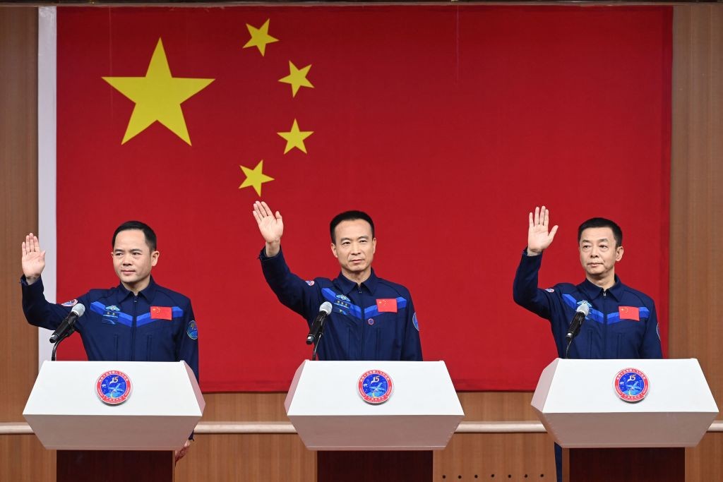 Los astronautas chinos Fei Junlong, Deng Qingming y Zhang Lu, tripulación de la misión del vuelo espacial Shenzhou-15, saludan en una conferencia de prensa en el Centro de Lanzamiento de Satélites de Jiuquan en la provincia de Gansu, en el noroeste de China, el 28 de noviembre de 2022, un día antes del lanzamiento. (Foto de -/CNS/AFP a través de Getty Images)