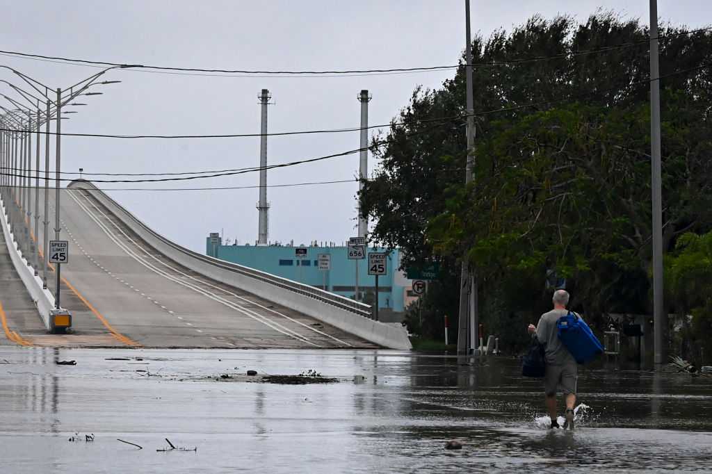 Un hombre con pertenencias personales camina en una calle inundada después de que el huracán Nicole toque tierra en Vero Beach, Florida, el 10 de noviembre de 2022 (Foto de EVA MARIE UZCATEGUI/AFP vía Getty Images)