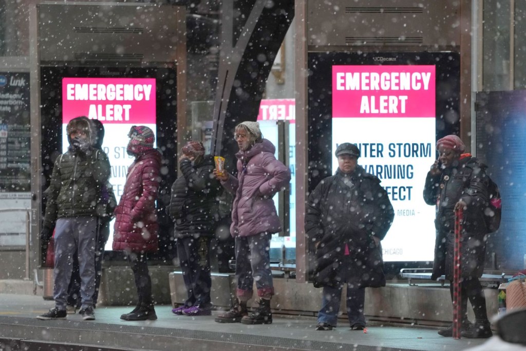 Viajeros de autobús esperan en una parada protegida en Chicago, el 22 de diciembre. (Crédito: Charles Rex Arbogast/AP)