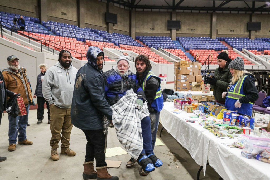 Voluntarios reciben a una persona sin hogar en un refugio del Broadbent Arena de Louisville, el 23 de diciembre. (Crédito: Leandro Lozada/AFP/Getty Images)