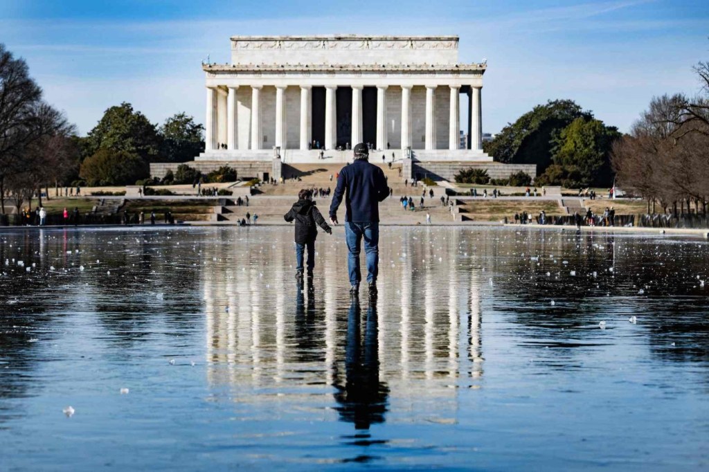 Un hombre y un niño caminan por el Reflecting Pool congelado hacia el Lincoln Memorial en Washington D. C., el 26 de diciembre. (Jim Watson/AFP/Getty Images)