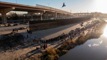 Migrantes hacen cola cerca del muro fronterizo después de cruzar el Río Bravo para entregarse a los agentes de la Patrulla Fronteriza de EE.UU. y solicitar asilo en El Paso, Texas, en una imagen tomada desde Ciudad Juárez, México, el 12 de diciembre.