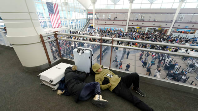 Un par de viajeros duermen mientras otros hacen fila para pasar por un control de seguridad en el Aeropuerto Internacional de Denver el viernes. (Foto: David Zalubowski/AP)