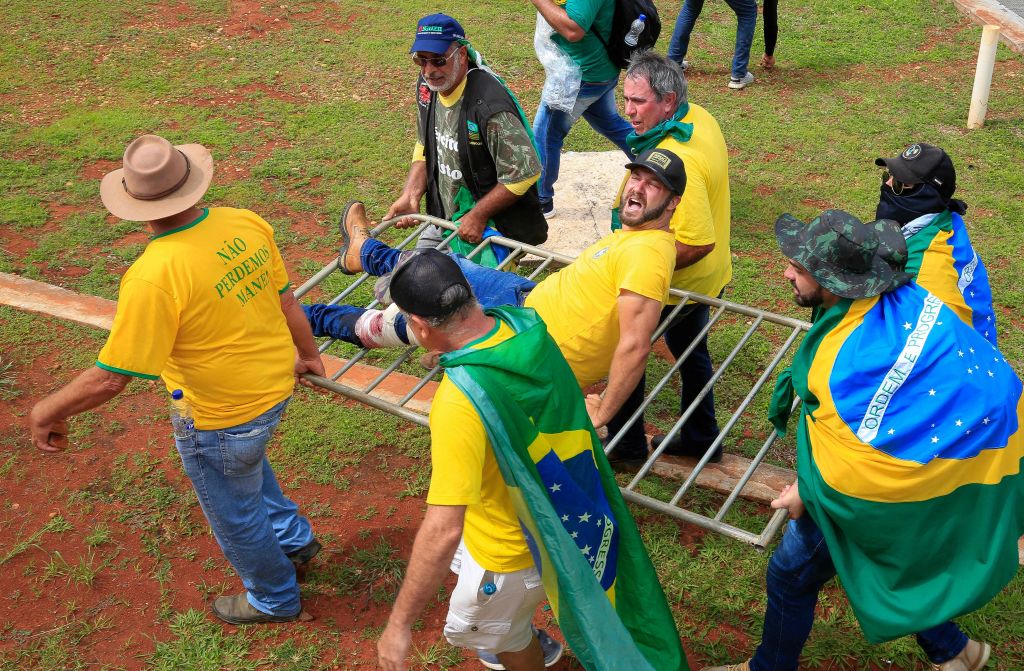 Un simpatizante del expresidente de Brasil Jair Bolsonaro es evacuado por sus compañeros tras resultar herido durante los enfrentamientos con la policía antidisturbios frente al Palacio Presidencial de Planalto, en Brasilia, el 8 de enero de 2023. (SERGIO LIMA/AFP vía Getty Images)