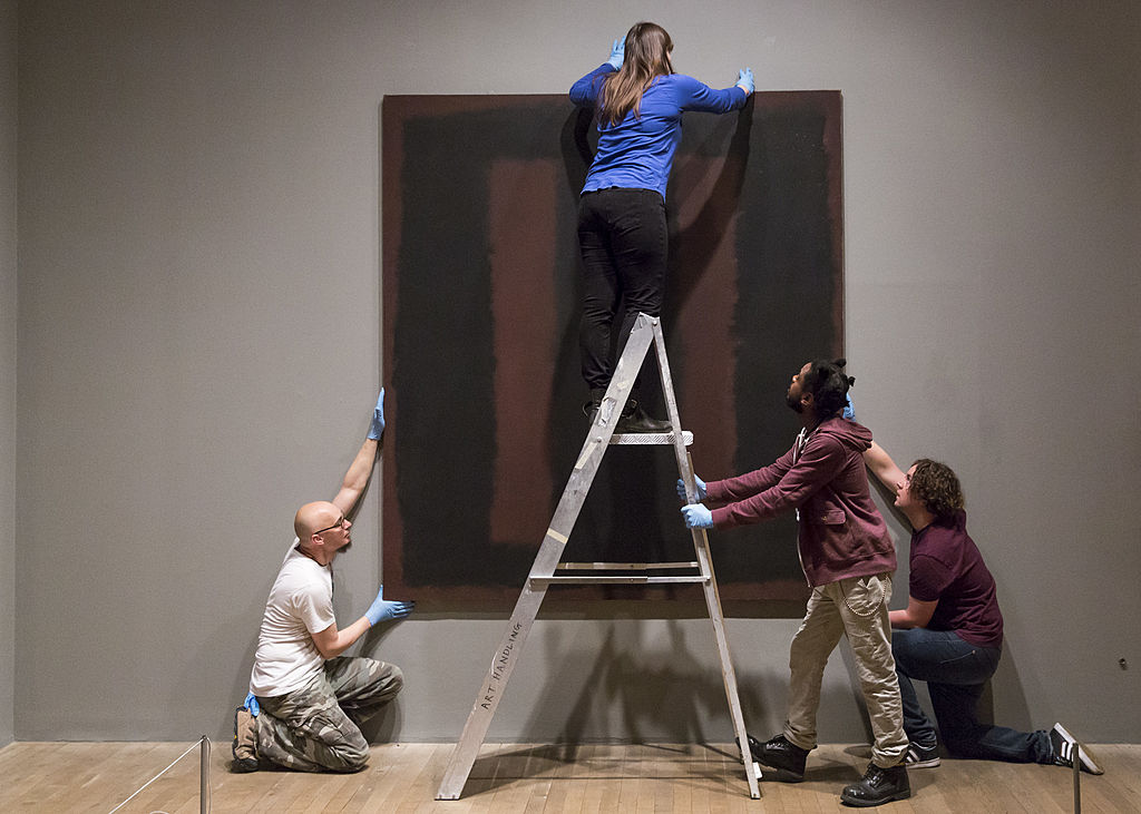 Especialistas en arte cuelgan la pintura del artista Mark Rothko "Negro sobre granate", de 1958 en el Tate Modern (Crédito Rob Stothard/Getty Images)
