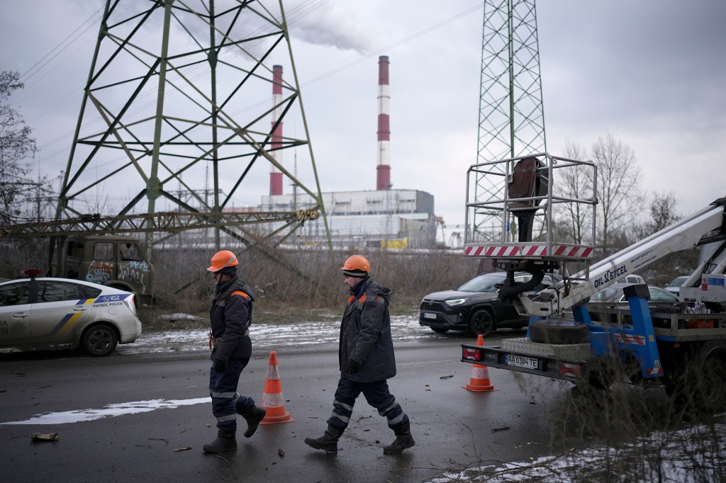 Trabajadores electricistas caminan junto a una central eléctrica tras un ataque con cohetes en Kyiv, Ucrania, el 26 de enero. (Crédito: Daniel Cole/AP)