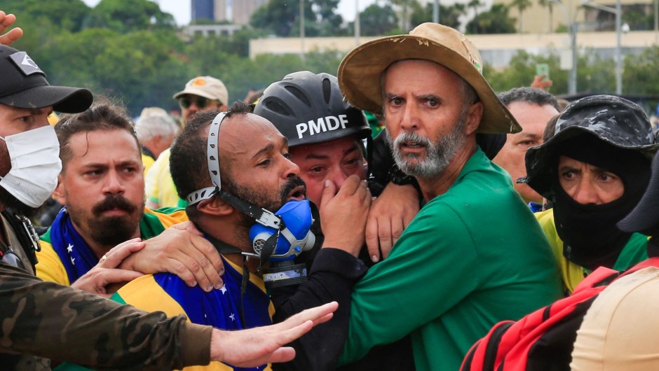 Simpatizantes de Bolsonaro asisten a un agente de la Policía Militar durante los enfrentamientos tras una invasión al Palacio Presidencial de Planalto. (SERGIO LIMA/AFP vía Getty Images)