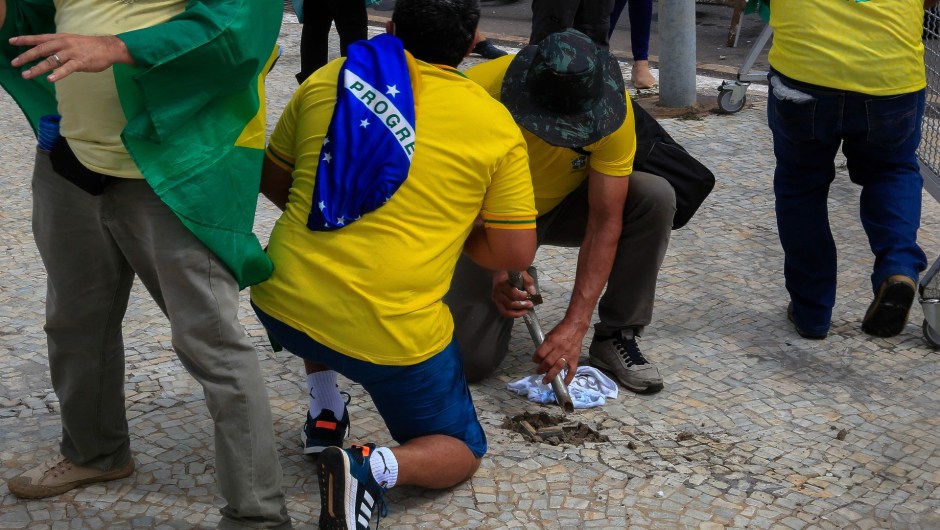 Simpatizantes de Bolsonaro dañan la acera para obtener piedras durante los enfrentamientos con la policía antidisturbios frente al Palacio Presidencial de Planalto. (SERGIO LIMA/AFP vía Getty Images)