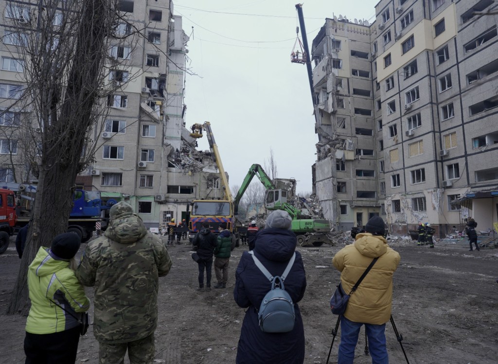 Residentes locales observan a los rescatistas que trabajan en un edificio residencial destruido tras el impacto de un misil, en Dnipro, el 16 de enero de 2023, en medio de la invasión rusa de Ucrania. (VITALII MATOKHA/AFP vía Getty Images)